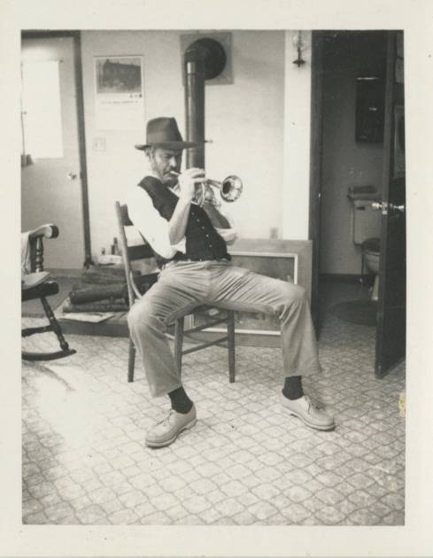 man playing trumpet sitting on chair